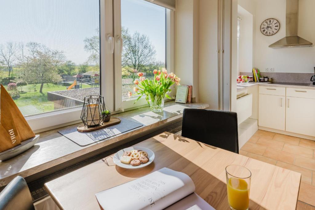 eine Küche mit einem Tisch und einem großen Fenster in der Unterkunft Landhaus Ferienwohnung 3, Bauernhof Hopp Vadersdorf in Fehmarn