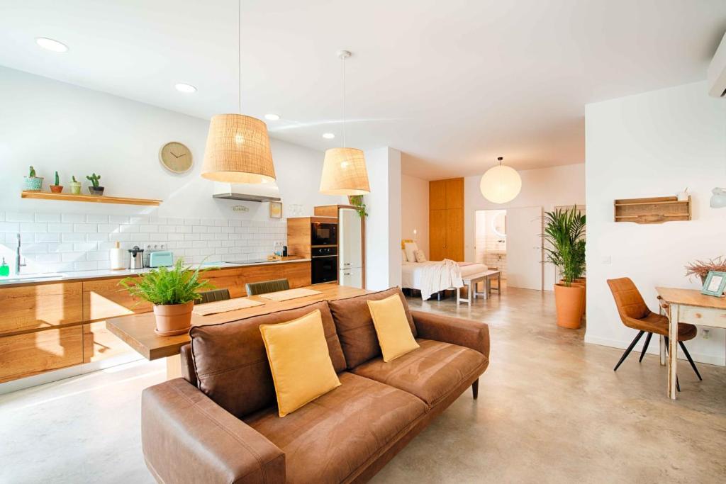 a living room and kitchen with a brown couch at Loft con piscina climatizada privada y parking in Figueres