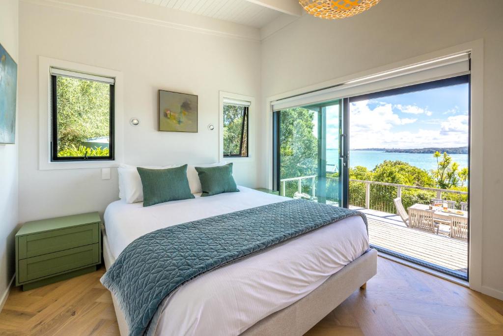 ein Schlafzimmer mit einem großen Bett und einem großen Fenster in der Unterkunft Black Cottage - Stay Waiheke in Waiheke Island
