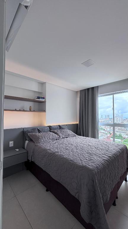 a bedroom with a bed and a large window at Quarto São João - familiar in Campina Grande