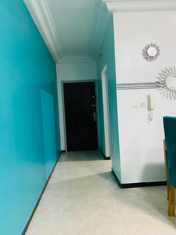 a hallway with a black door and a blue wall at Khurtis 225 in Abidjan