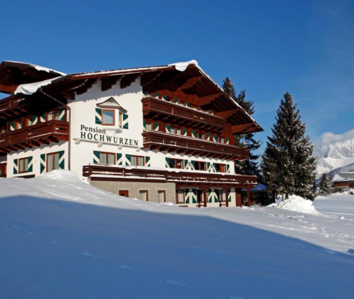 un bâtiment avec de la neige devant lui dans l'établissement Hotel Garni Hochwurzen, à Schladming