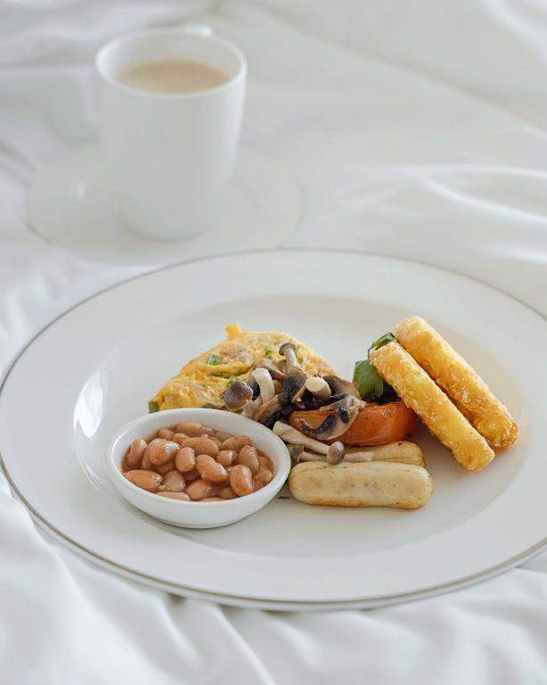A plated breakfast of eggs, beans, vegetables and fried sides with coffee.