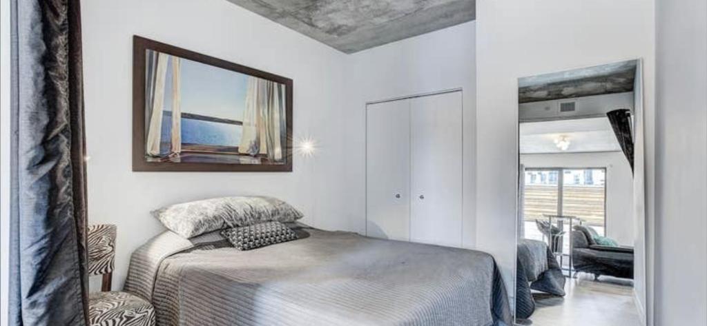 a white bedroom with a bed and a mirror at INCh in Montréal