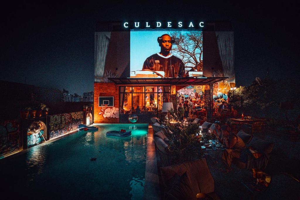A rooftop pool beside a brightly lit, graffiti-covered entertainment building at night.