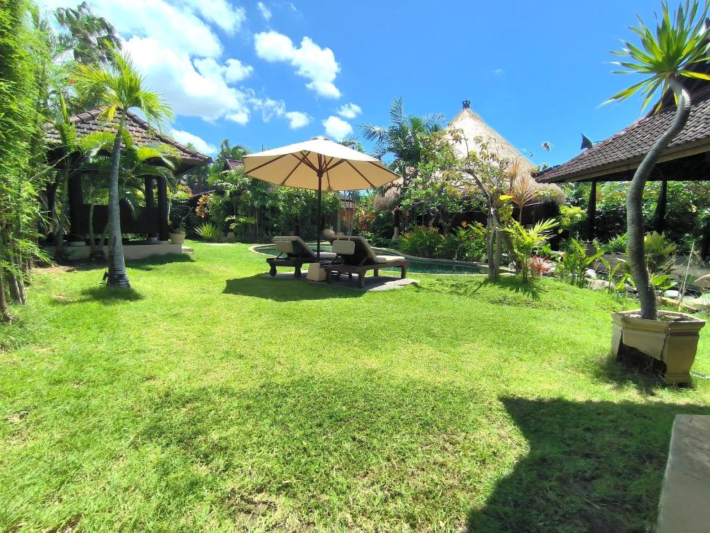a lawn with a picnic table and an umbrella at Villa Plawa Asri in Seminyak