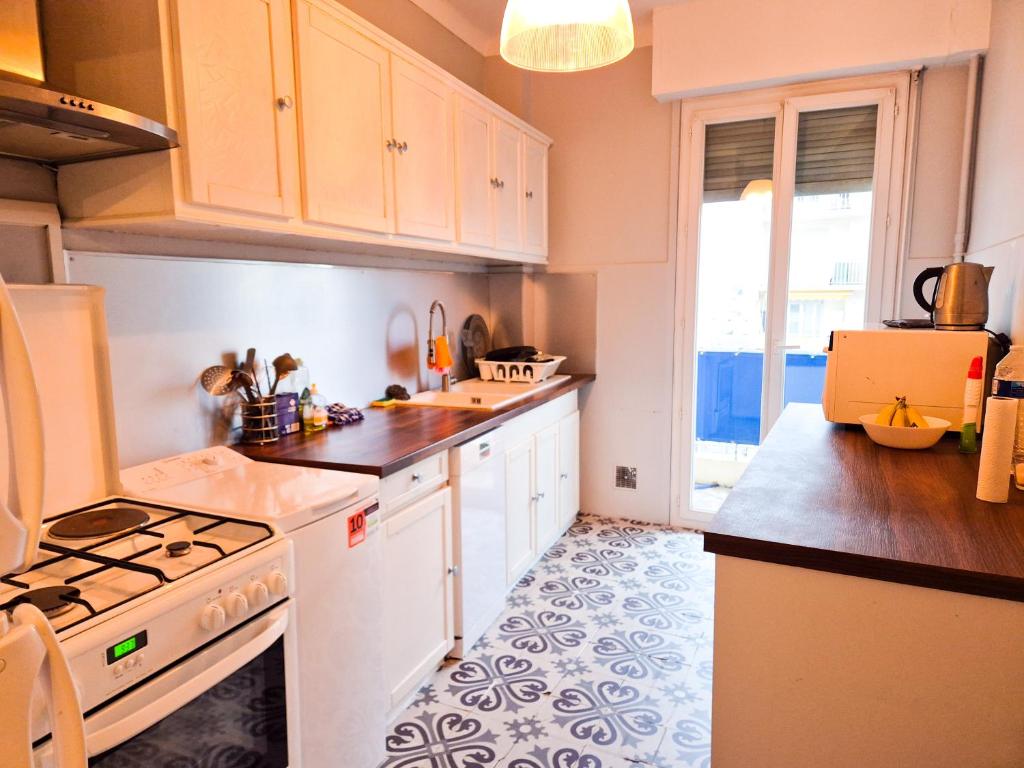 une cuisine avec des armoires blanches et un four à plaques de cuisson dans l'établissement Appartement Promenade des Anglais, à Nice