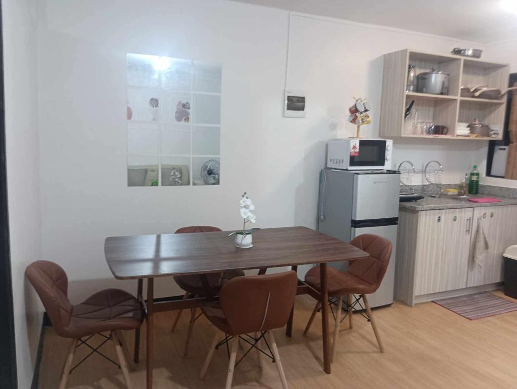 a kitchen with a wooden table and chairs and a refrigerator at Kellys Abode in Marilao