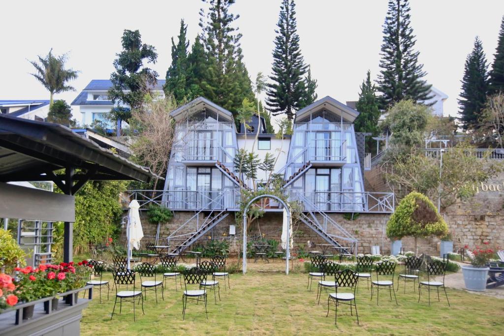Un grupo de sillas y mesas frente a un edificio. en DD Hospitality - Mây Bách Đà lạt, en Da Thien