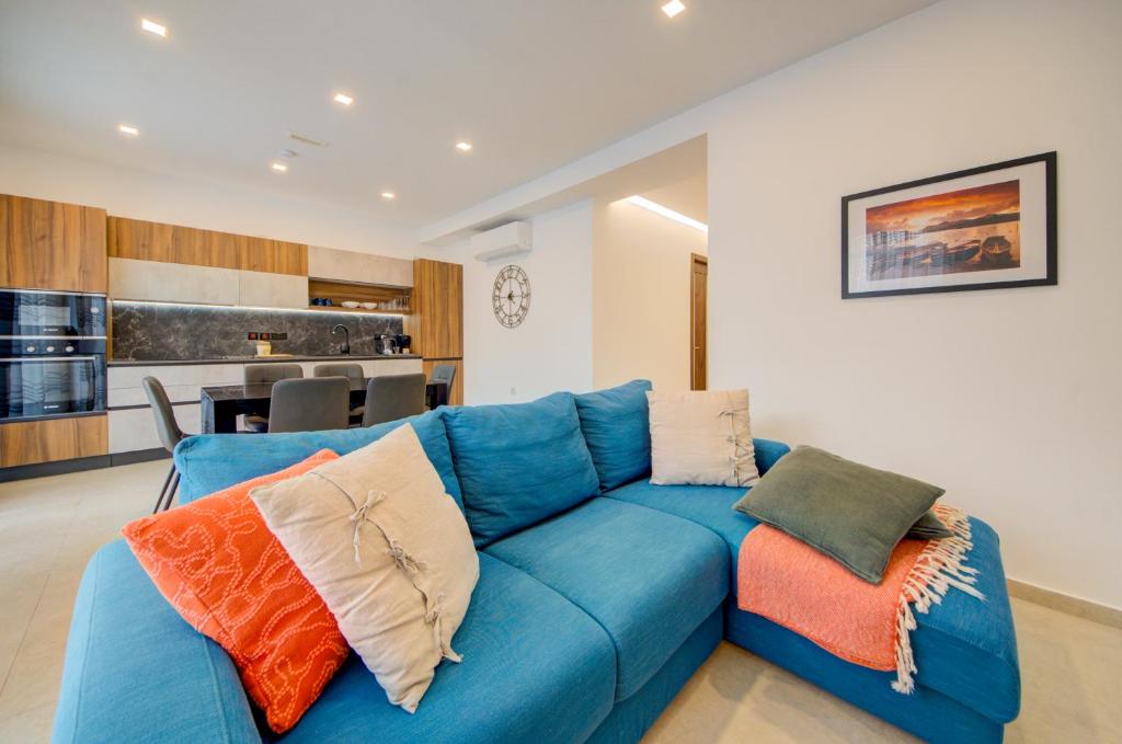 a blue couch with pillows in a living room at St Julians Apartment in St. Julianʼs