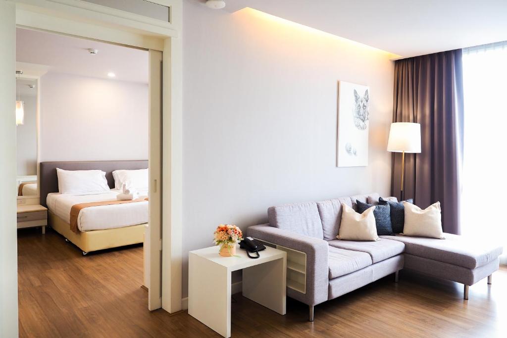 チェンマイにあるTHE KANNAS Hotel & Serviced Apartment, Chiang Mai SHA Certifiedのソファとベッドのあるリビングルーム