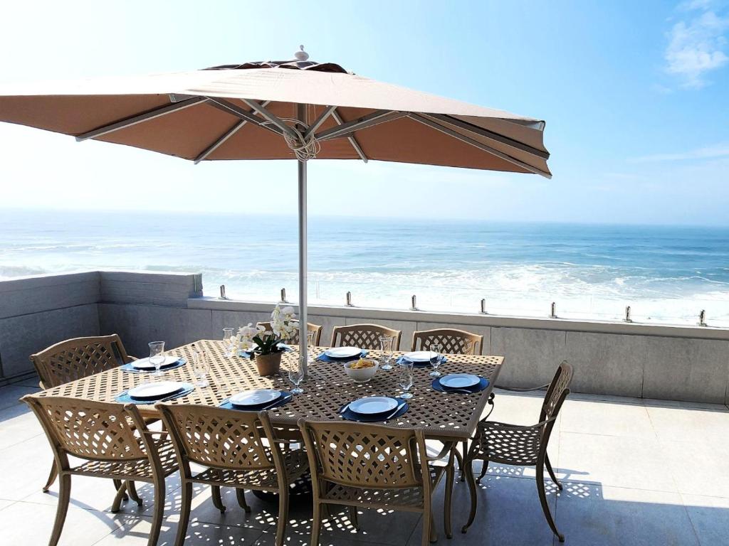 a table and chairs with an umbrella and the ocean at Frinton on Sea 12 in Ballito