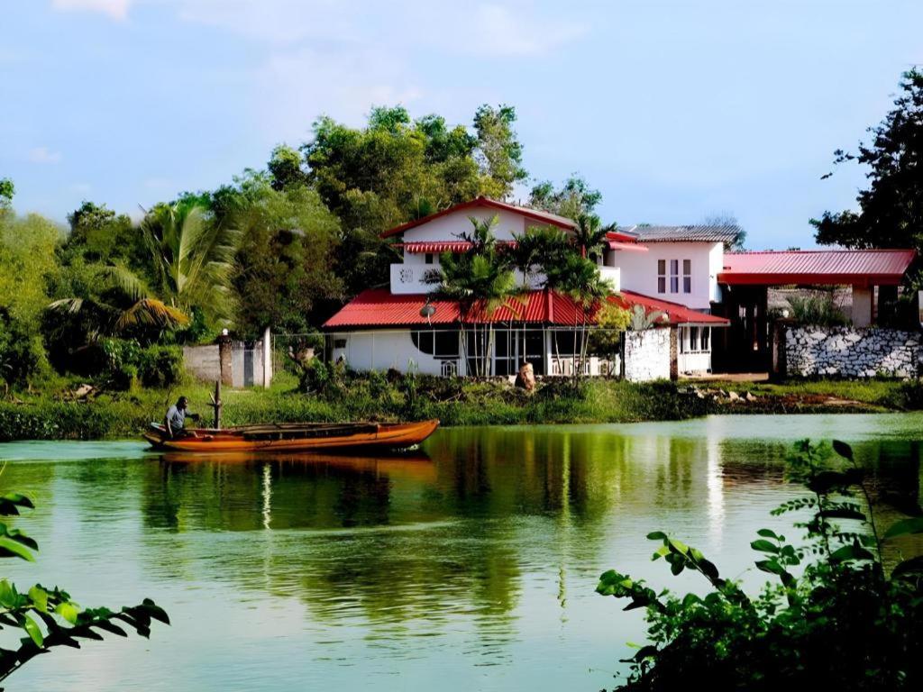 een man in een boot op het water voor een huis bij Riverside Hotel Colombo in Dandugama