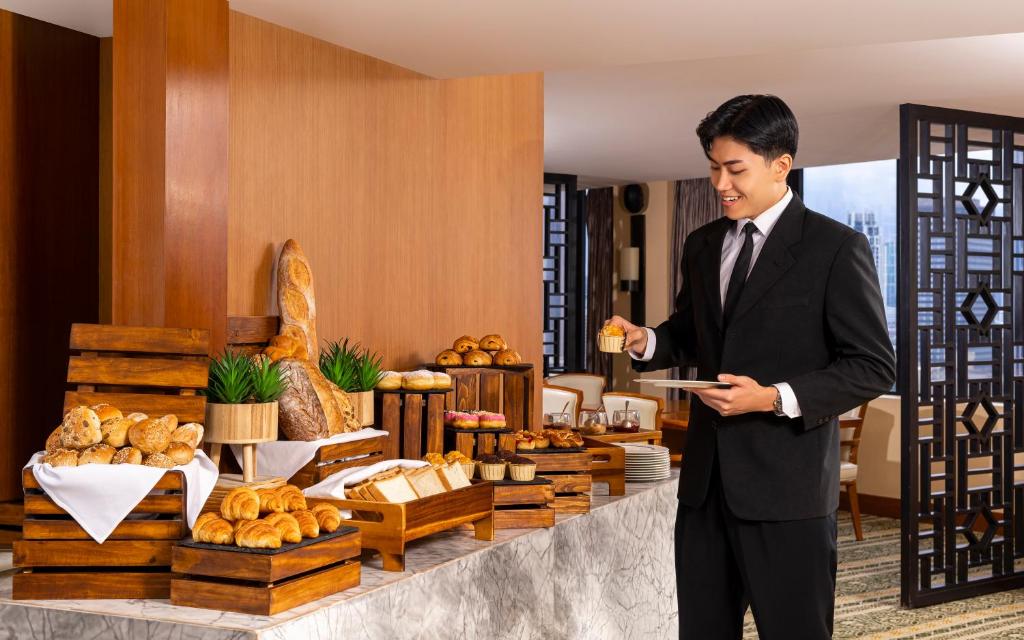 a man in a suit holding a plate of food at Mandarin Oriental, Jakarta in Jakarta