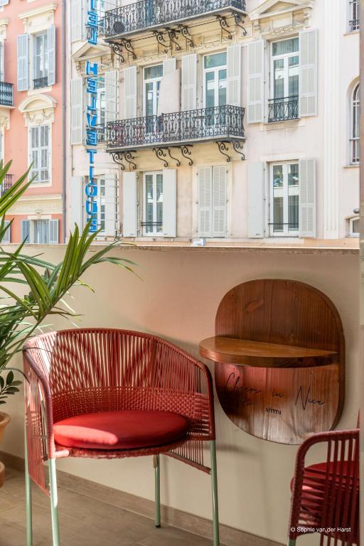 a red chair and a table in front of a building at Aparthotel AMMI Nice Lafayette in Nice
