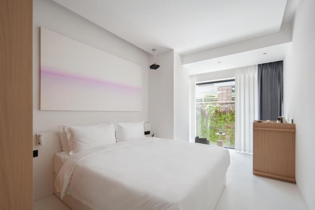 a white bedroom with a large bed and a window at Shenzhen INNOGYM Hotel in Shenzhen