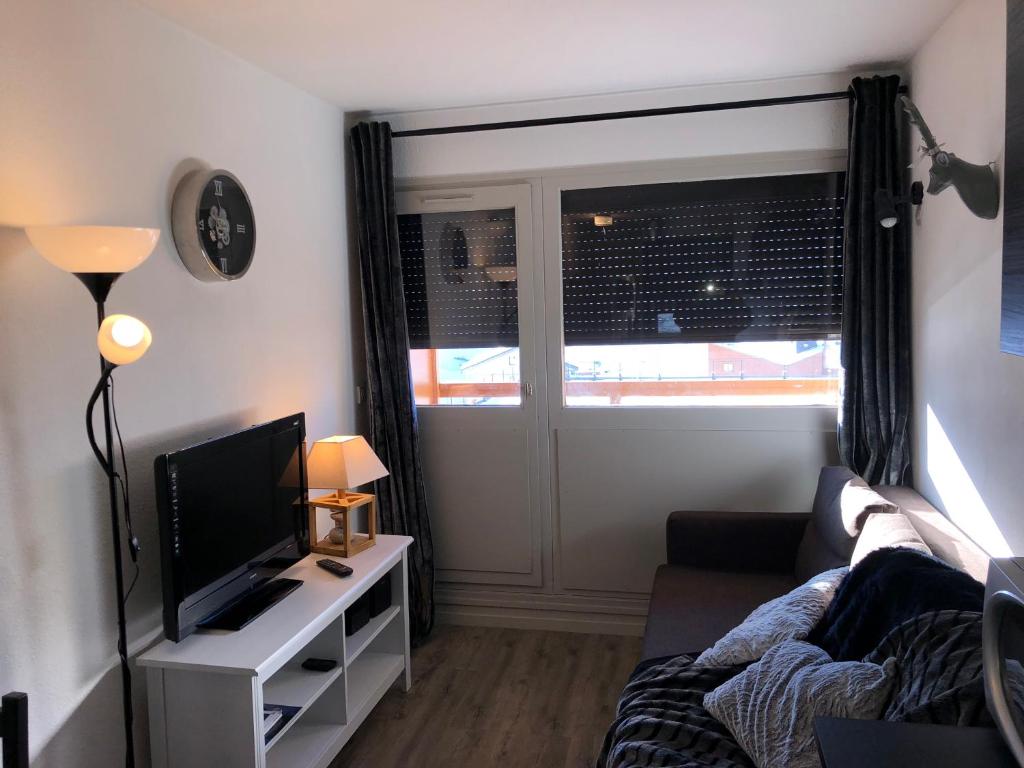 Una sala de estar con un sofá y un televisor. en VA THORENS studio SUD VUE 180 WIFI, en Val Thorens