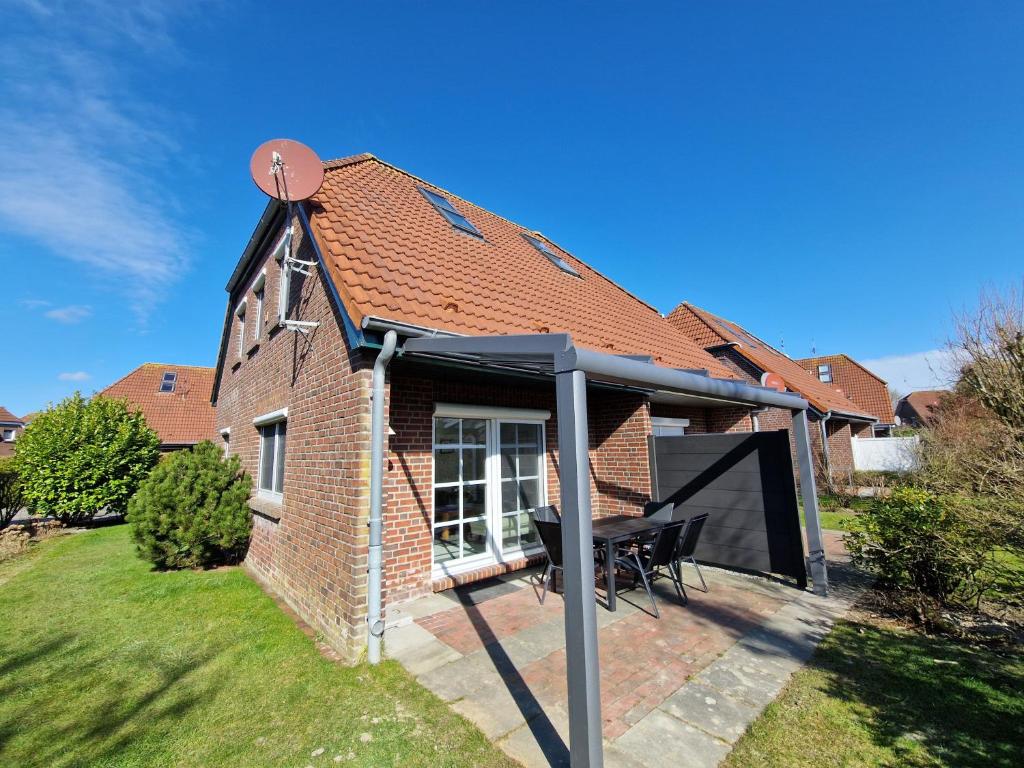 a patio with a black gazebo on a house at Nr 97 - Ferienhaus Uferstraße in Carolinensiel