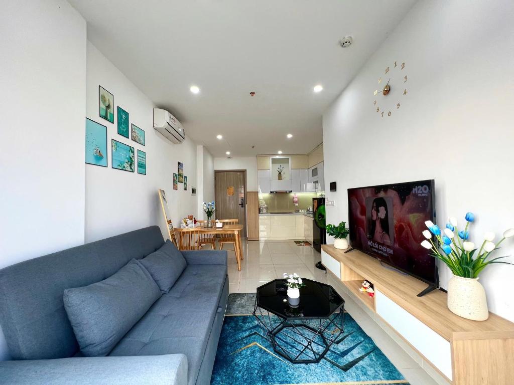 un salon avec un canapé bleu et une télévision dans l'établissement Tom's House 2 Apartment, à Thôn Văn Dương