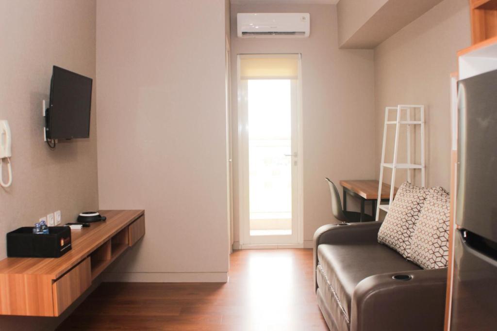 un soggiorno con un divano e un tavolo di Fancy and Comfy 2BR Apartment at Springlake Summarecon By Travelio a Bekasi