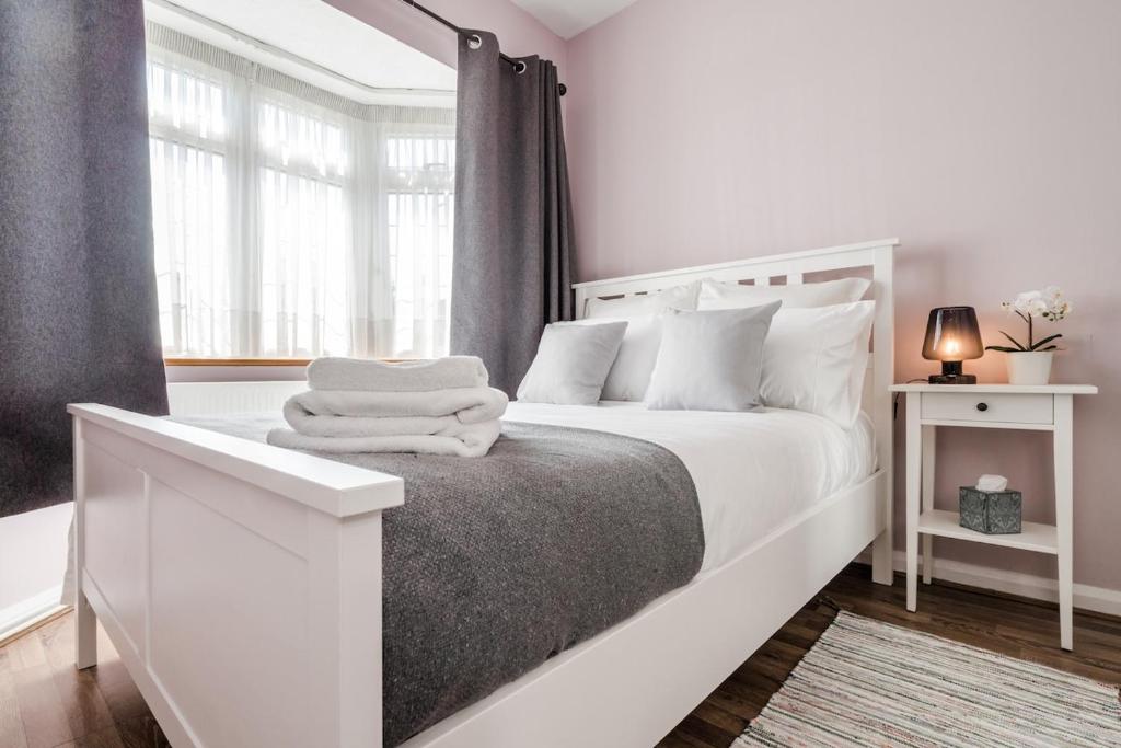 a white bedroom with a white bed and a window at Entire 4-Bedroom Home Surrey in Sunbury Common