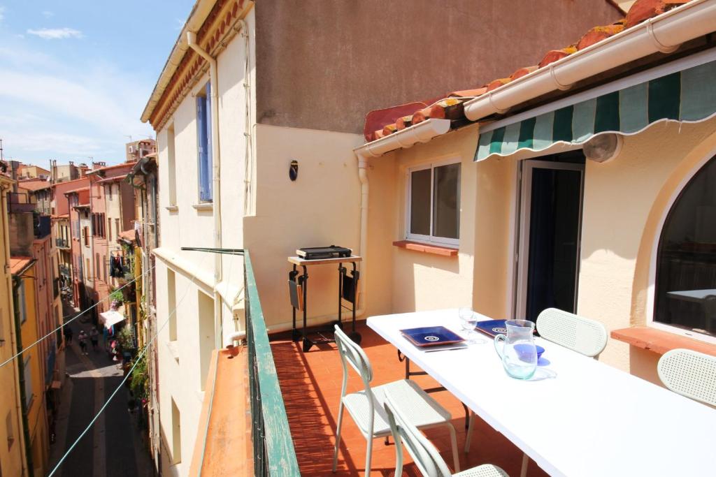 un balcon avec une table et des chaises sur un immeuble dans l'établissement Le Poisson Bleu, à Collioure