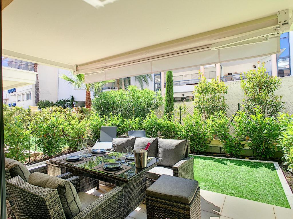 d'une terrasse avec des chaises en osier, une table et de la pelouse. dans l'établissement Palm beach apartment with swimming pool in a residence, à Cannes