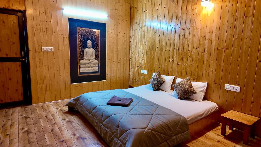 Acoustic heaven Cottage jibhi في Jibhi: غرفة نوم بها سرير عليه صورة بوذا