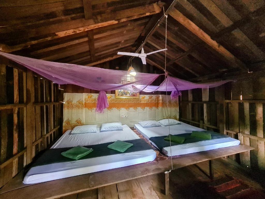 two beds in a wooden room with a ceiling at Ratanakiri Homestay & Jungle Trek in Banlung