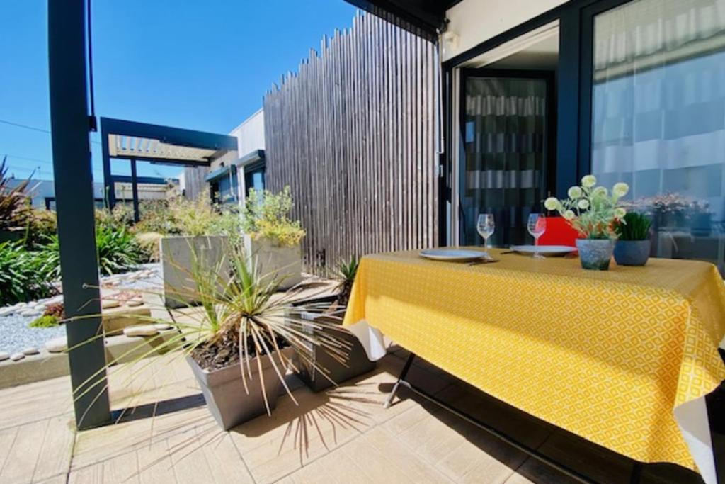 un patio avec une table jaune et quelques plantes en pot dans l'établissement Quiet house with terrace and south-facing garden, à La Rochelle