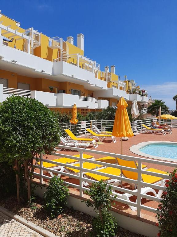 a resort with a pool and chairs and a building at Royal Cabanas Golf by Amandio Batista in Cabanas de Tavira