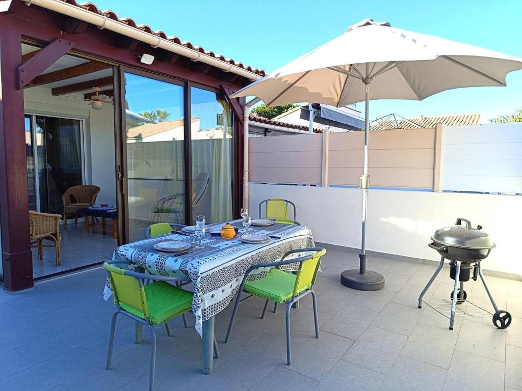 une table avec des chaises et un parasol sur une terrasse dans l'établissement Superbe pavillon dans résidence avec piscine -parking privatif -6CYC119, à Saint Cyprien Plage