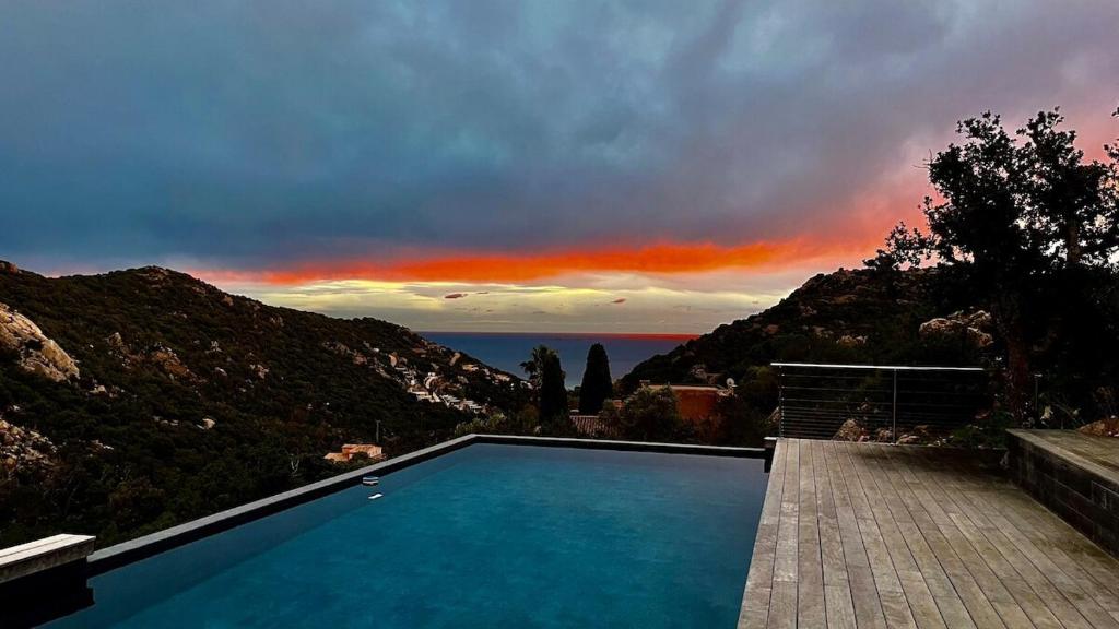 a swimming pool with a sunset in the background at Villa Porra 100m2, pleine nature, piscine, vue mer in Porto-Vecchio