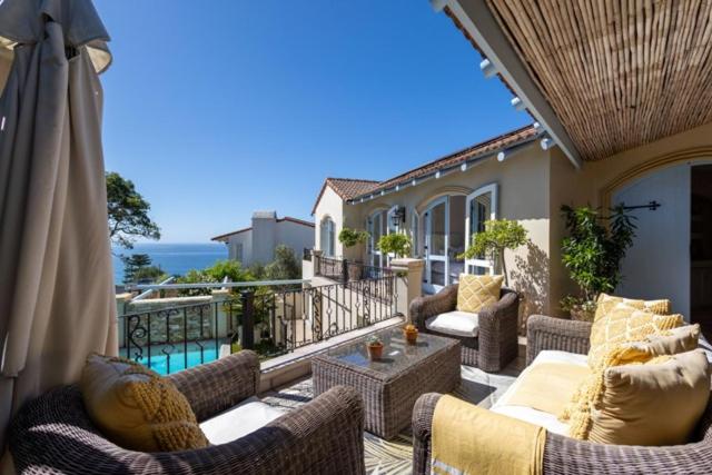 a patio with couches and an umbrella on a balcony at Lavender hill in Plettenberg Bay