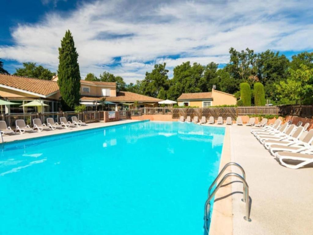 a large swimming pool with lounge chairs and a resort at Maison dans village de vacances 5 pers climatisé piscine in Gaujac
