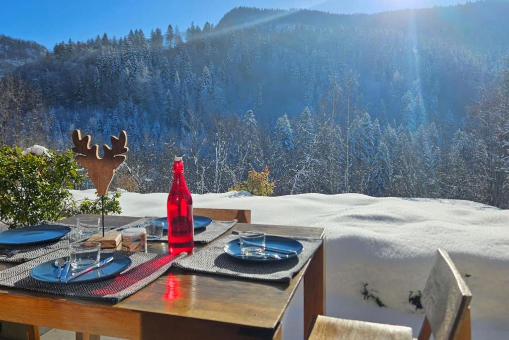 une table avec des assiettes et une bouteille rouge au-dessus dans l'établissement 3 apartment with terrace and 3 bedrooms, à Saint-Jean-de-Sixt