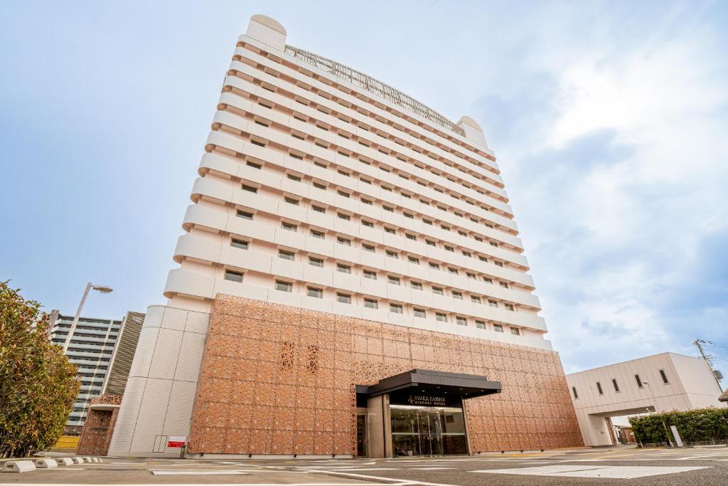 a tall white building with a brick wall at Osaka Kansai Airport Hotel Kansai Airport 2 station in Izumi-Sano