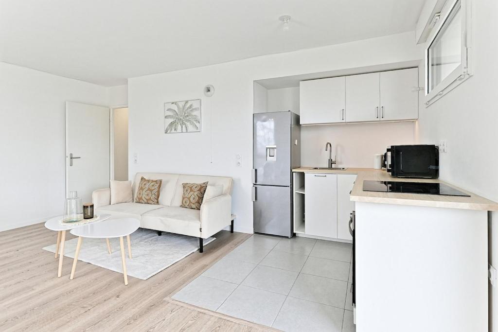 une cuisine et un salon avec un canapé et une table dans l'établissement Spacieux 3 chambres avec balcon - Colombes, à Colombes