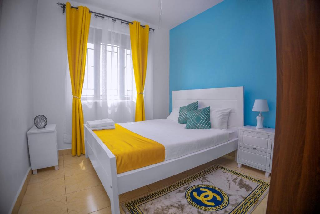 a bedroom with a white bed with yellow curtains at Tranquil - 2 bedroom Spacious Condo with WIFI, 20 mins from KAMPALA CENTER in Kampala