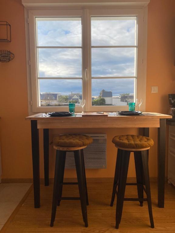 une table avec deux tabourets devant une fenêtre dans l'établissement Petit appartement au centre de Concarneau, à Concarneau