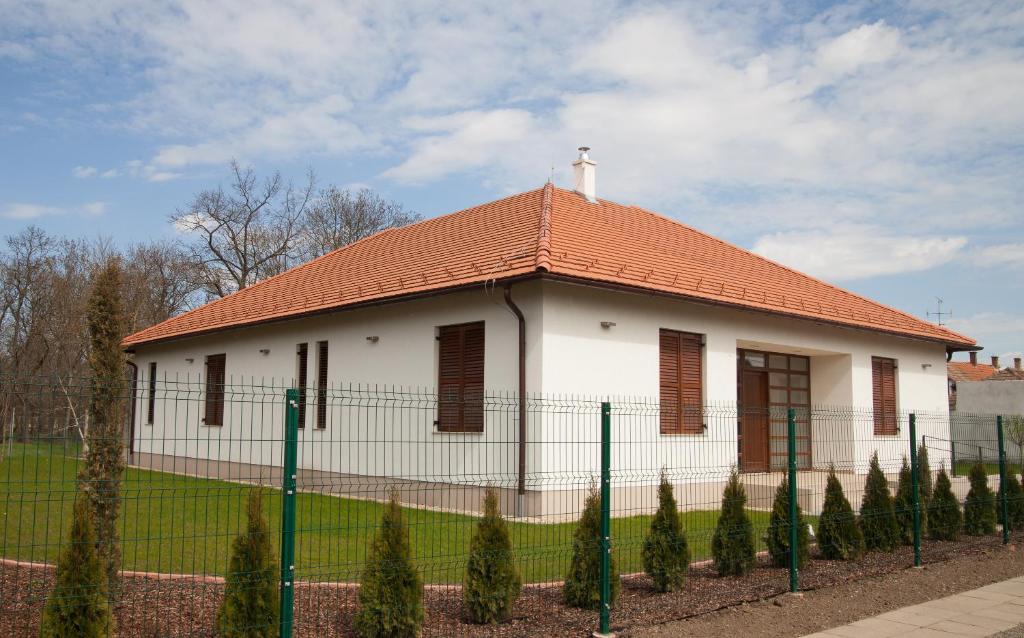 un edificio blanco con techo rojo y valla en Kakasszéki Vendégház en Székkutas