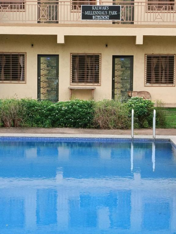 a blue swimming pool in front of a building at Kalwars Millennials Park in Karjat