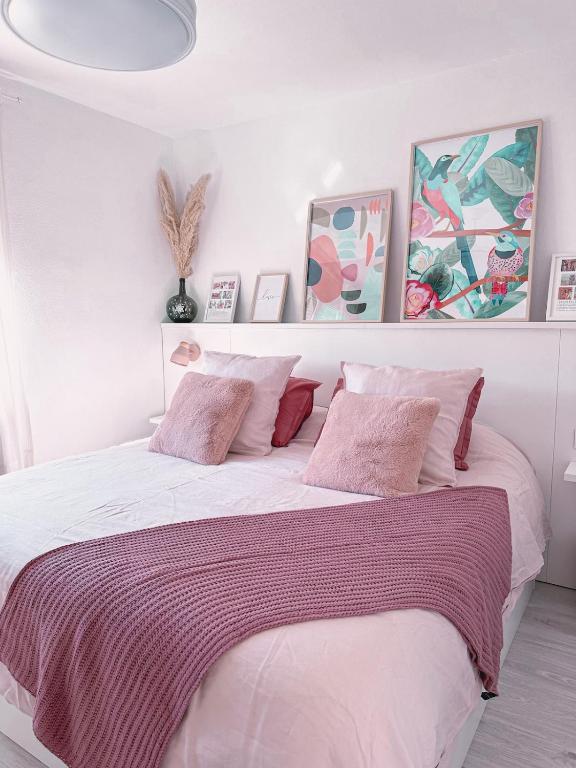 a white bedroom with a large bed with pink pillows at Casa rosa completa-patio- BBQ-columpios-buhardilla in Campillo de Altobuey