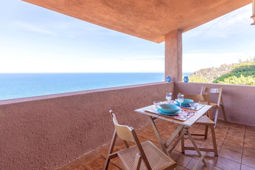 a table and chairs on a balcony with the ocean at Il Belvedere Di Achille in Costa Paradiso
