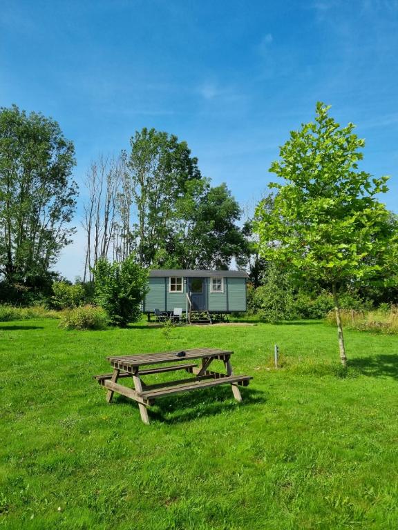 une table de pique-nique et une maison dans un champ dans l'établissement Les trois bergers, à Serley