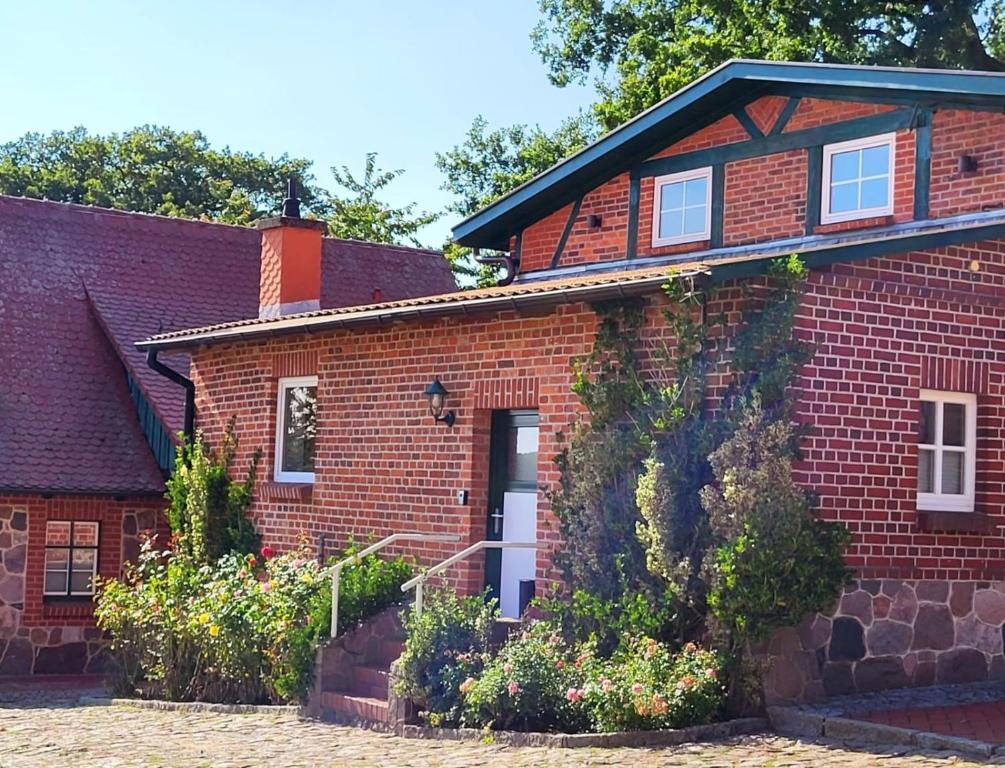 a red brick house with flowers in front of it at Ferienwohnung Hof Schacht in Penkow