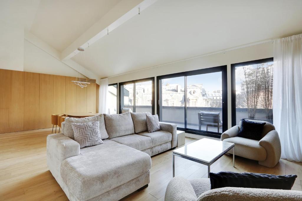 un salon avec un canapé, des chaises et des fenêtres dans l'établissement Pick A Flat's apartment Place Victor Hugo - Rue des Belles Feuilles, à Paris