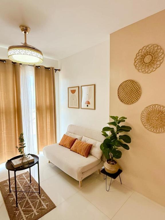 a living room with a couch and a potted plant at One-Bedroom and Studio Apartment near SM City , IT Park and Ayala Mall - NO PARKING at Bamboo Bay Community in Mandaue City