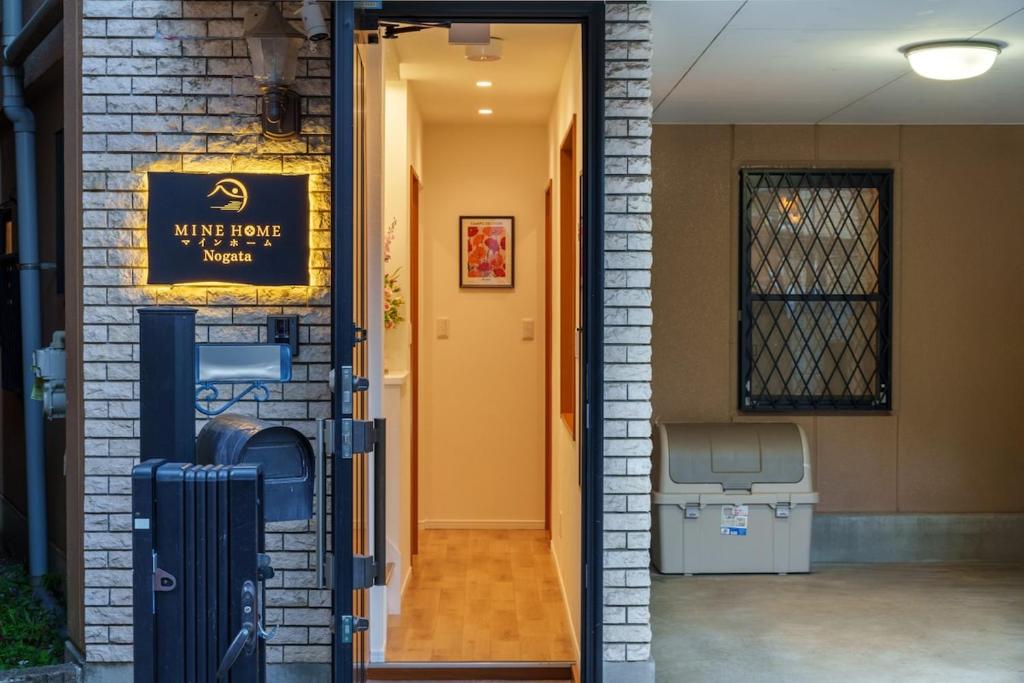 uma porta para uma casa com um sinal em 121T MINE HOME野方 nogata MH野方 98m貸切 野方駅から徒歩1分 新宿まで6駅17分 寝室4 広々一軒家 リノベーション em Tóquio
