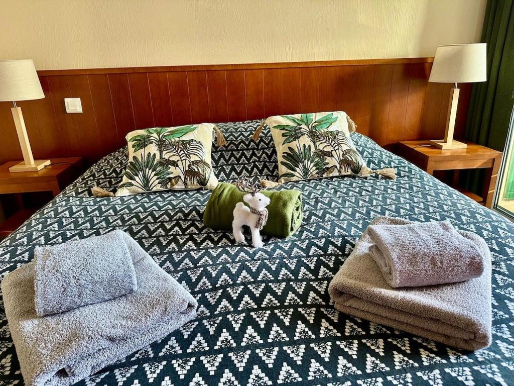 a bed with a stuffed animal on top of it at nid douillet au milieu des pins entre lac et océan in Carcans